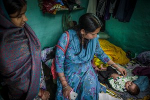 Rima, a Save the Children community health volunteer, on a check-up visit with Chotti, who recently gave birth to baby Naveen. Rima, 39, is a Save the Children community health volunteer living in Delhi. She works in a slum area in South Delhi called VP Singh Camp. Her role is to mobilise the community around health care issues, spreading awareness about good sanitation and best practices relating to maternal health care and childbirth. Rima enjoys her job, meeting and helping people in the local community and says she has seen many changes and improvements with the introduction of community health volunteers. One mother she recently helped was Chotti who lives in the VP Singh camp. Chotti had previously lost three babies, but after meeting Rima finally gave birth to a healthy baby boy called Naveen. Rima was able to help Chotti gain access to government health care, advise her to attend regular check-ups throughout her pregnancy, at the Save the Children mobile health unit (MHU), and finally give birth at a hospital in South Delhi. Rima has been able to visit Chotti at home since she gave birth and offer her advise on breast feeding, health and on general cleanliness with a new born baby.